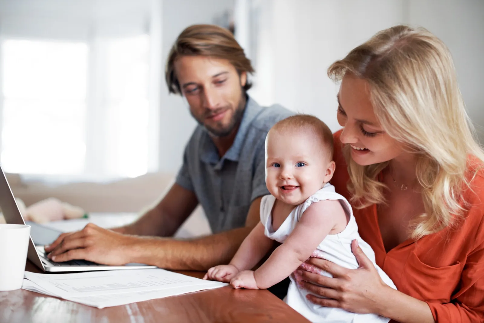 Eltern mit Baby sehen gemeinsam Unterlagen durch