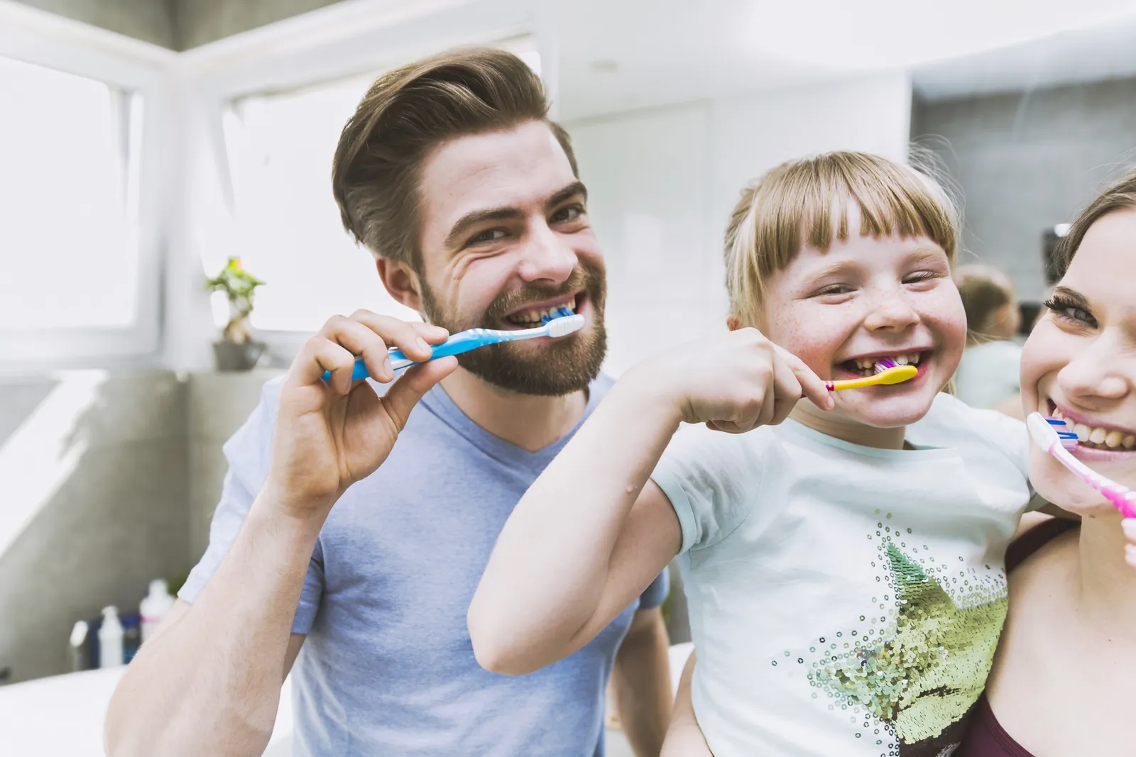 Vater und Tochter putzen lachend die Zähne