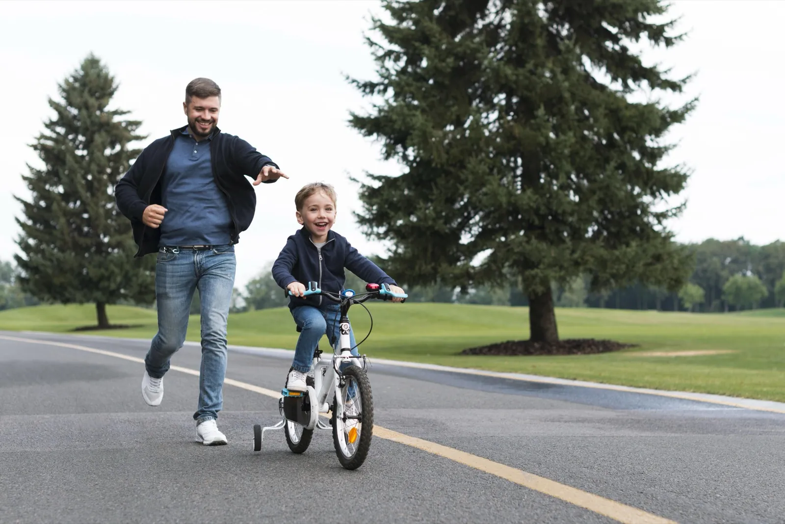 Vater läuft neben seinem Sohn auf dem Fahrrad her