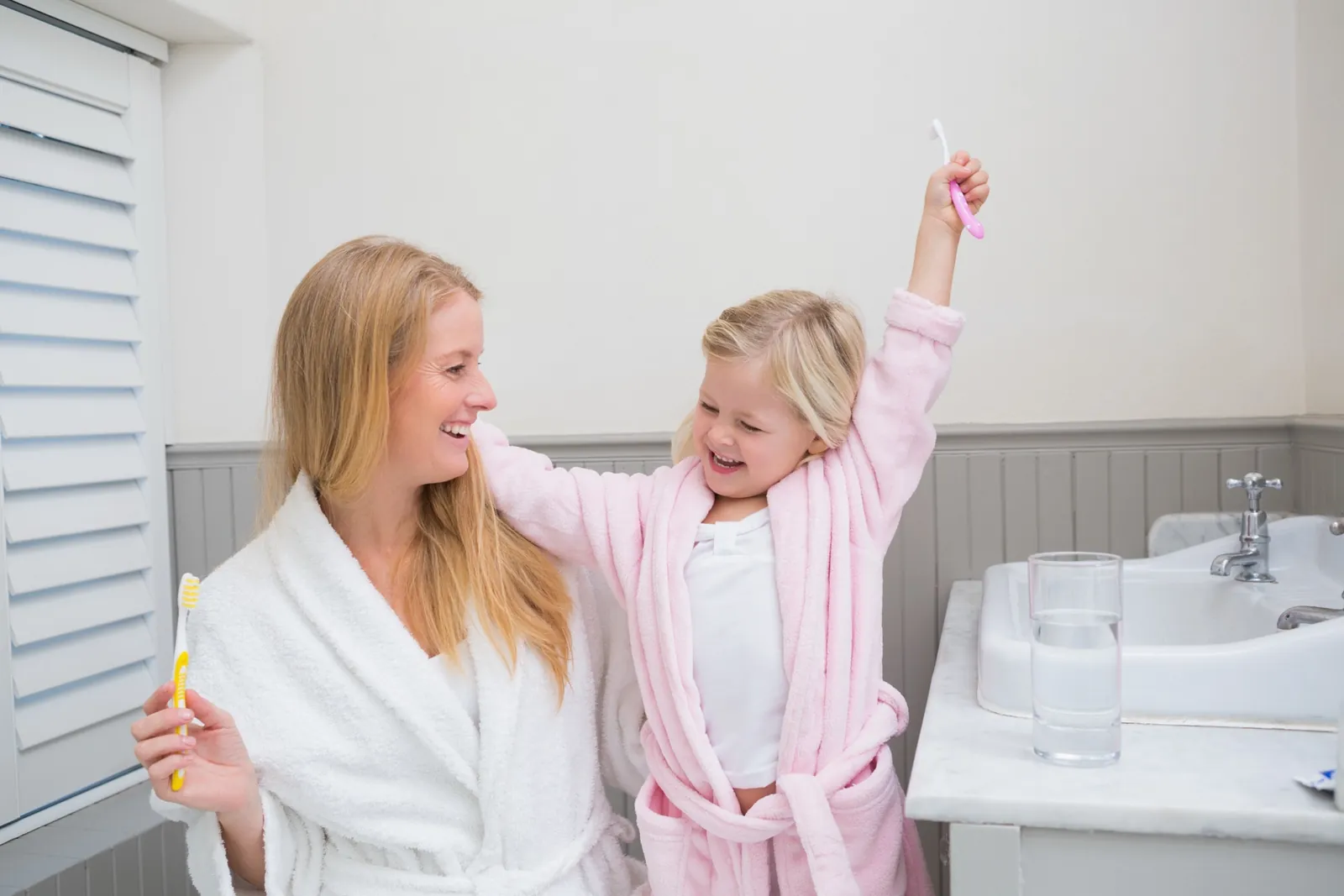 Mutter und Tochter putzen gemeinsam Zähne